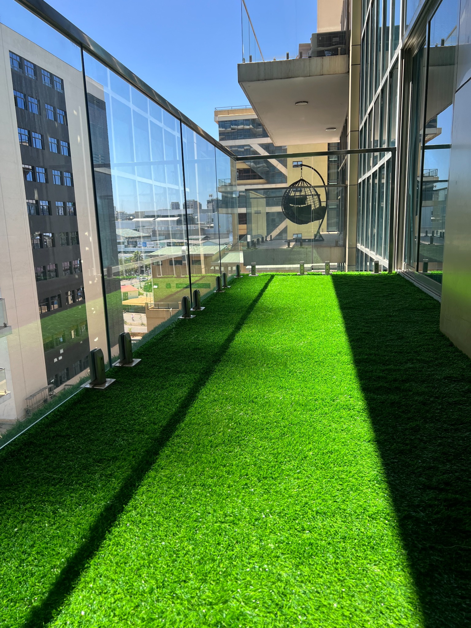 Small apartment balcony after artificial grass and seating