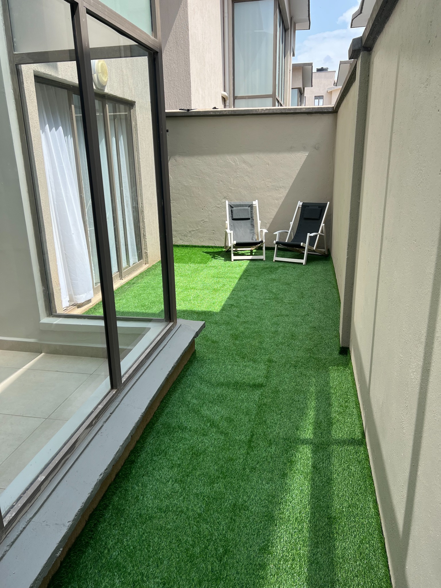 Narrow courtyard after artificial grass installation