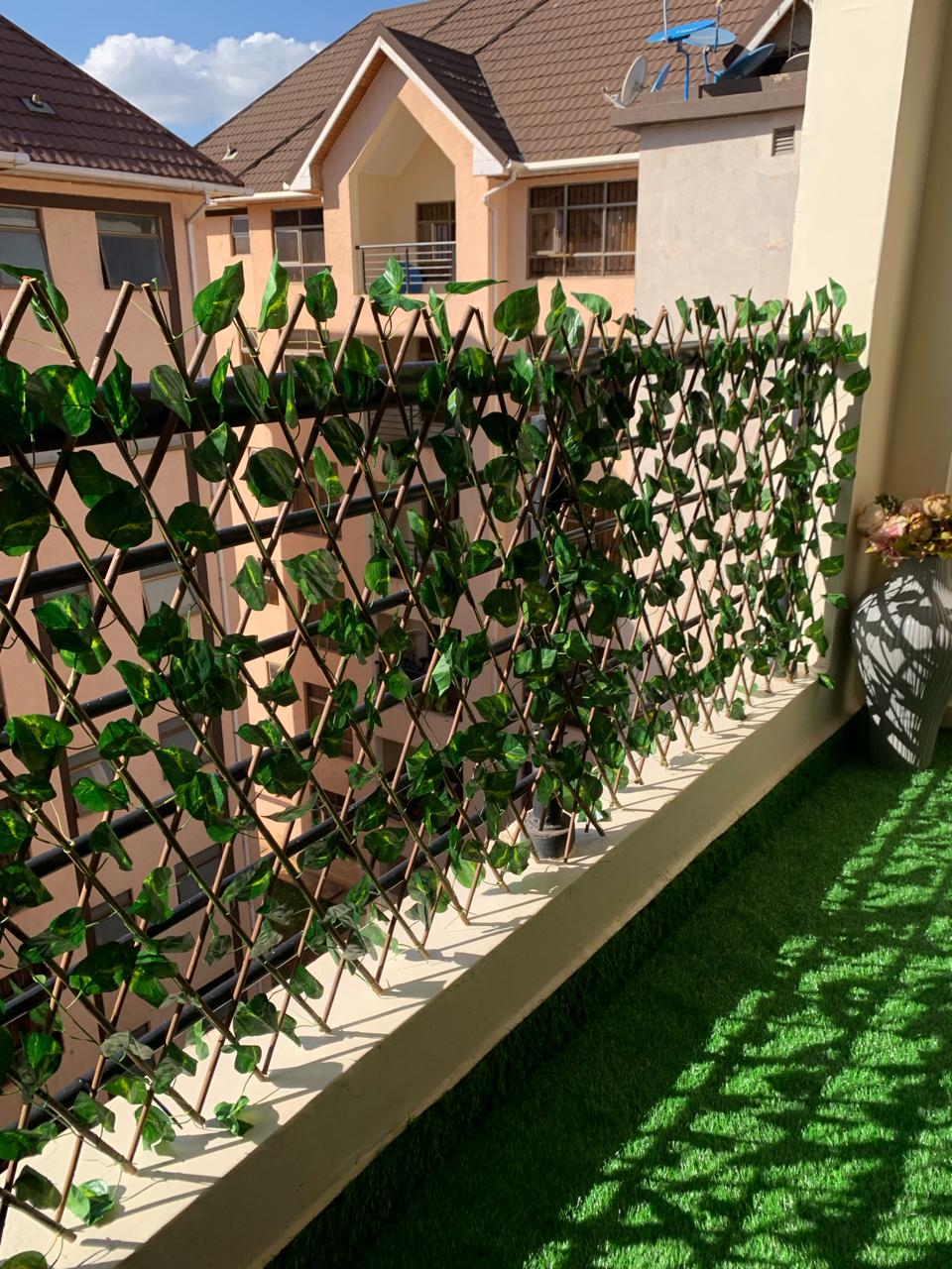 Expandable artificial leaf privacy fence installed on a balcony